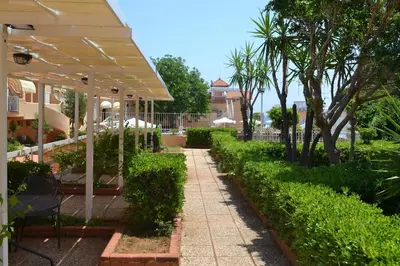 a garden with a walkway with bushes and trees at La Dimora di Alice in Palermo
