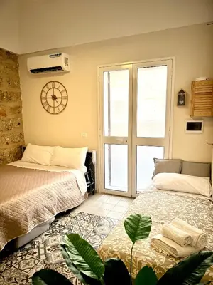 a bedroom with two beds and a clock on the wall at La Casetta dell'Architetto in Cinisi