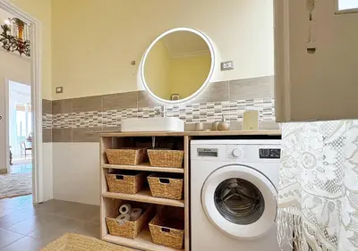 a bathroom with a washing machine and a mirror at Solemar Sicilia - Palazzo Tiglio in Porticello