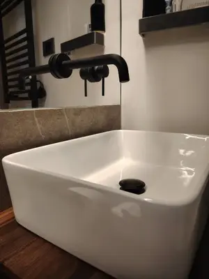 a white bathroom sink with a black faucet at Cappuccetto Rosso Sweet Modern Suite Palermo in Palermo