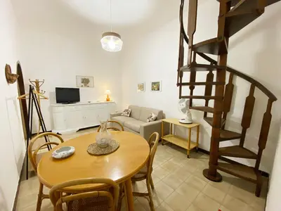 a living room with a table and a spiral staircase at Il Vialetto in Mondello
