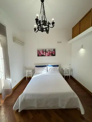 a bedroom with a white bed and a chandelier at Dimora 51 in Palermo