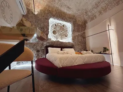 a bedroom with a bed with a stone wall at Corona Suite & Rooms in Palermo