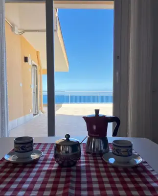 a tea set on a table with a view of the ocean at A' Terrazza in Santa Flavia