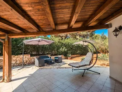 a patio with a chair and an umbrella at Villa Betta Cuntrariusa con piscina privata e jacuzzi a Scopello in Castellammare del Golfo
