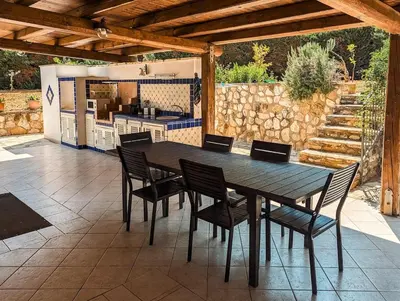 a wooden table and chairs on a patio at Villa Betta Cuntrariusa con piscina privata e jacuzzi a Scopello in Castellammare del Golfo