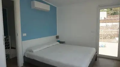 a bedroom with a white bed and a blue wall at Giardino degli Allori, Villa Manfredi with Pool in Castellammare del Golfo