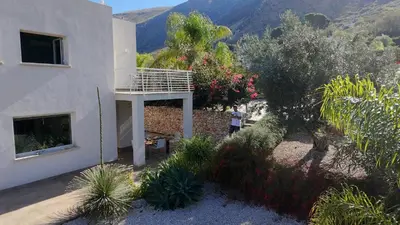 a person standing next to a house with a balcony at Giardino degli Allori, Villa Manfredi with Pool in Castellammare del Golfo