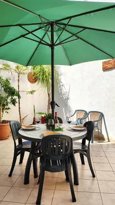 a table with chairs and a green umbrella at Casa Bougainville, Mare e Relax in San Vito lo Capo