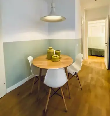 a dining room with a wooden table and white chairs at Tarzana’ home in Palermo