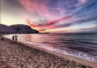 two people walking on the beach at sunset at Casetta Tiffany Mondello in Mondello