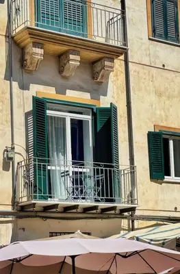 a building with a window with green shutters and an umbrella at Dimora Al-Noor in Palermo