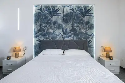 a bedroom with a large bed with a blue and white wallpaper at Santerasmo rooms Charm in Palermo