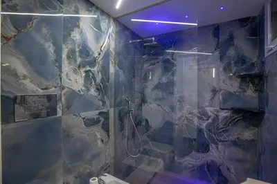 a bathroom with a shower with a stone wall at Santerasmo rooms Charm in Palermo