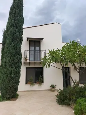 a white house with a balcony and a large tree at Villa Deluxe in Campofelice di Roccella