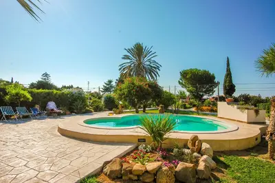 a swimming pool in a garden with a landscaping at Villa Deluxe in Campofelice di Roccella