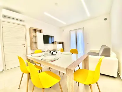 a white bedroom with a bed with a yellow pillow at Appart Perla, posizione strategica in Castellammare del Golfo