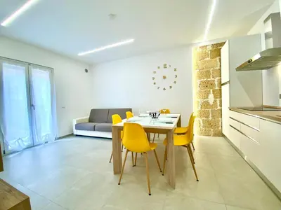 a white bedroom with a yellow pillow on a bed at Appart Perla, posizione strategica in Castellammare del Golfo