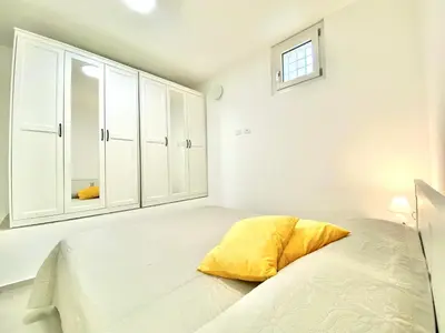 a white bedroom with a bed and a cabinet at Appart Perla, posizione strategica in Castellammare del Golfo