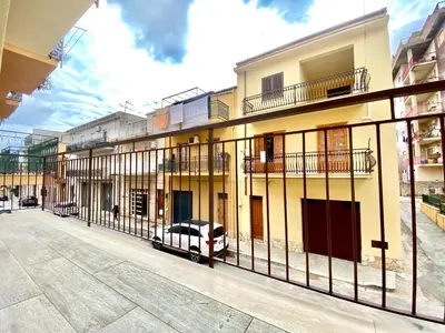 a fence in front of a building with a car at Appart Perla, posizione strategica in Castellammare del Golfo