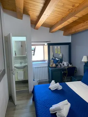 a bedroom with a blue bed and a bathroom at U muragliuni 2 in Lascari