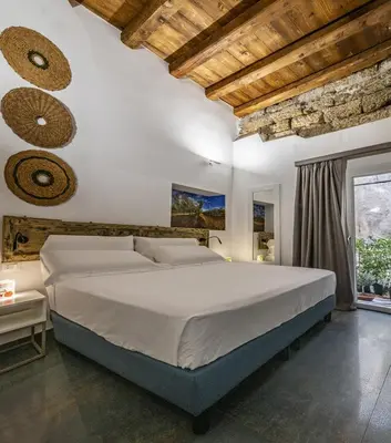 a bedroom with a large bed and a stone wall at Ballarooms Experience in Palermo