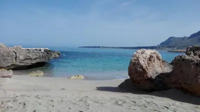 a beach with rocks and the blue water at Aquilone in Castelluzzo