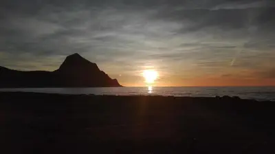 a sunset on the beach with a mountain in the background at Aquilone in Castelluzzo
