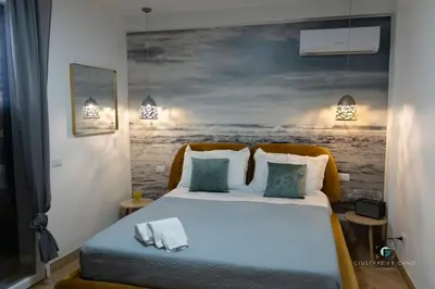 a bedroom with a bed with a painting on the wall at ESSE Homes Sant Elia in Santa Flavia