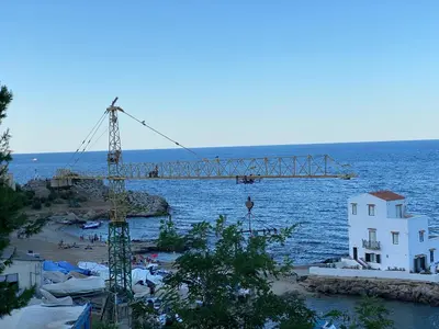 a crane on a beach next to the water at ESSE Homes Sant Elia in Santa Flavia