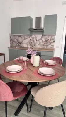a wooden table with pink chairs and plates on it at Cocciu d'amuri a casa in Terrasini