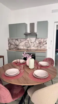 a wooden table in a kitchen with pink chairs at Cocciu d'amuri a casa in Terrasini