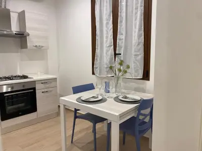 a kitchen with a white table and blue chairs at Appartamento Dante 2 in Alcamo