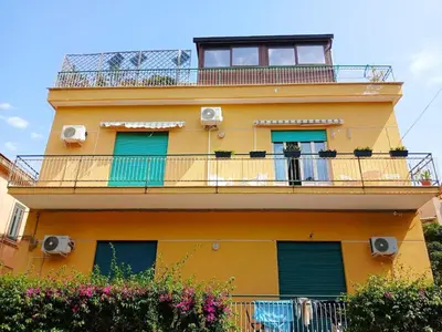 a yellow building with a balcony with green doors at Casa Cavarretta in Palermo