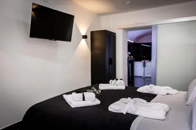 a room with a bed with towels and a flat screen tv at Palermo Luxury Rooms Black in Palermo