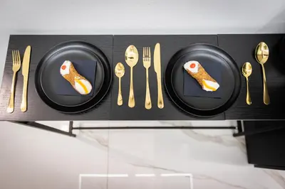 a shelf with black plates and gold forks and knives at Palermo Luxury Rooms White in Palermo