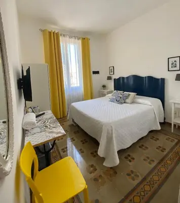 a bedroom with a bed and a yellow chair at Alvorada Rooms in Palermo