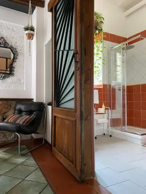 an open door in a room with a chair and a shower at Alvorada Rooms in Palermo