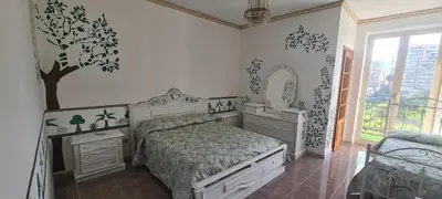 a bedroom with a bed and a tree on the wall at Cottage I Sollazzi in Palermo