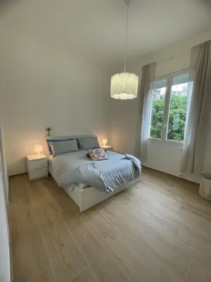 a white bedroom with a bed and two lamps at Iazzu Apartament in Palermo