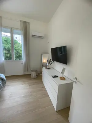 a white living room with a tv on a wall at Iazzu Apartament in Palermo