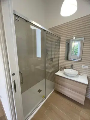 a bathroom with a glass shower and a sink at Iazzu Apartament in Palermo