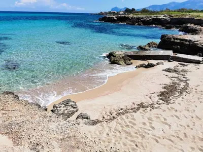 a sandy beach with the ocean and rocks at Homedaf in Carini