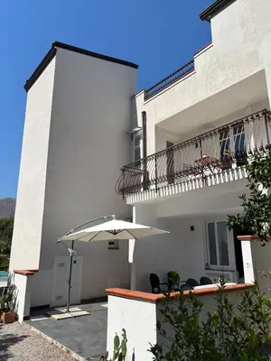 a white building with a balcony and an umbrella at Villa Grasta, Nuova Esclusiva con Piscina in Capaci