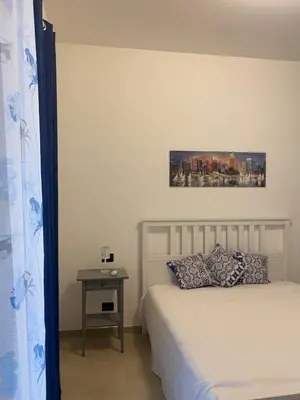 a bedroom with a bed and a side table with a picture on the wall at Ma Home in Cinisi