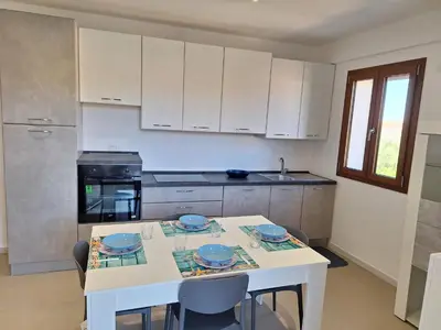 a kitchen with a white table with blue plates on it at La Marina Pool Villa in Trappeto