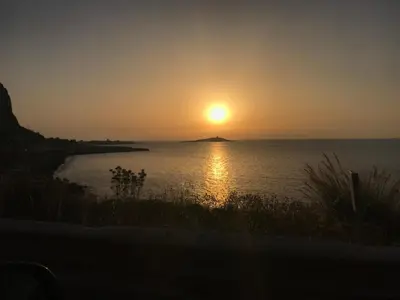 a sunset over the water with an island in the distance at Summer House in Isola delle Femmine