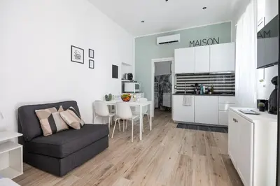 a living room with a black couch and a kitchen at Uditore Mini Apartment in Palermo