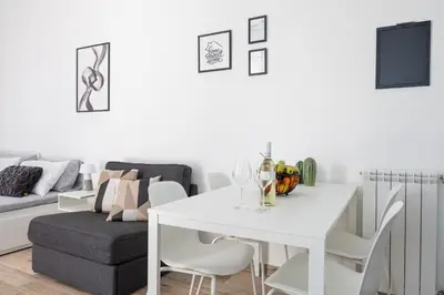 a white dining room with a white table and a couch at Uditore Mini Apartment in Palermo