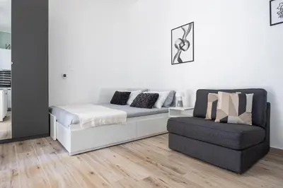 a white bedroom with a couch and a chair at Uditore Mini Apartment in Palermo